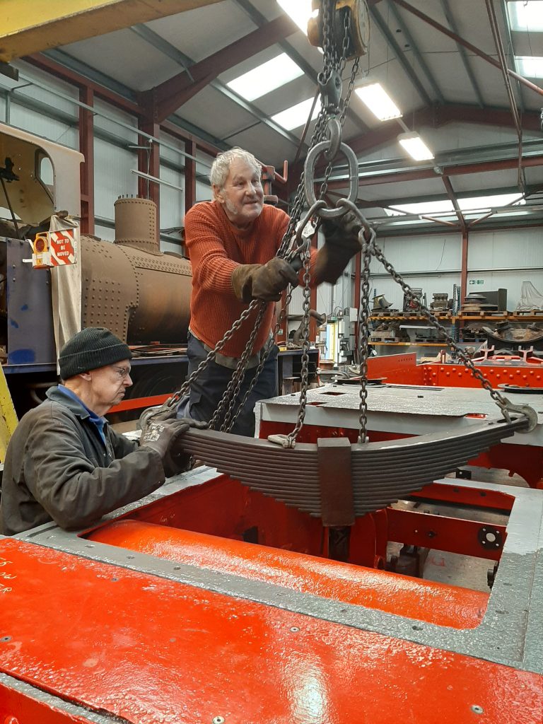 John Dixon and Keith Brewer lifting a radial truck spring into position